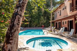 a swimming pool in a yard next to a house at Pousada Y-Goá in Bertioga