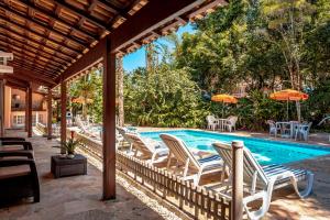 a swimming pool with lounge chairs and umbrellas at Pousada Y-Goá in Bertioga