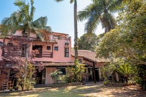 a pink house with palm trees in front of it at Pousada Y-Goá in Bertioga