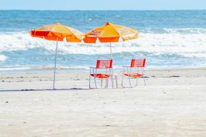two chairs and two umbrellas on the beach at Pousada Y-Goá in Bertioga