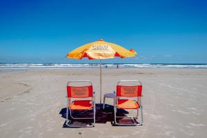 two chairs and an umbrella on the beach at Pousada Y-Goá in Bertioga