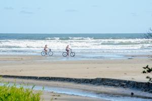 two men riding bikes on the beach at Pousada Y-Goá in Bertioga