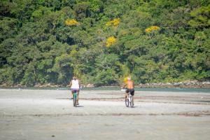 two people riding their bikes on the beach at Pousada Y-Goá in Bertioga