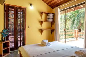 a bedroom with a bed and a large window at Pousada Y-Goá in Bertioga
