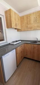 a kitchen with wooden cabinets and a white dishwasher at Motel Lavanda in Avşa Adası