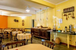 a restaurant with tables and chairs in a room with yellow walls at Pousada Y-Goá in Bertioga