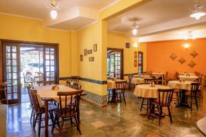 a restaurant with tables and chairs and yellow walls at Pousada Y-Goá in Bertioga