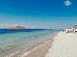 a sandy beach with chairs and the ocean on a sunny day at Motel Lavanda in Avsa Adasi