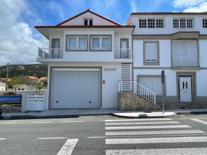 une maison blanche avec deux portes de garage dans une rue dans l'établissement Apartamento en Carnota, à Carnota