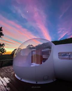 una cúpula de cristal sentada en una terraza con puesta de sol en La Estela Bubble Glamping, en Mazamitla