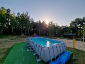 a swimming pool with chairs around it in a park at Domki Wrzosowe Wzgórza Nr1 in Horyniec