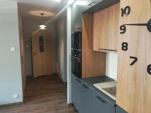 a kitchen with wooden cabinets and a counter top at Apartament Shadow in Białystok +4 photos