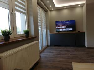 a waiting room with a flat screen tv and windows at Apartament Shadow in Białystok