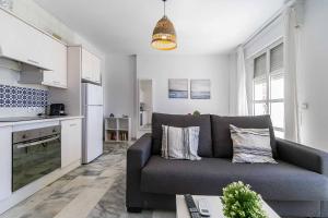 a living room with a couch and a kitchen at Sur Suites Astigi Vista Mar in Fuengirola