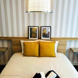 a bed with yellow pillows and two pictures on the wall at rosario inn porto in Porto