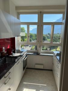 a kitchen with white cabinets and a large window at SAVOY 26 in Interlaken