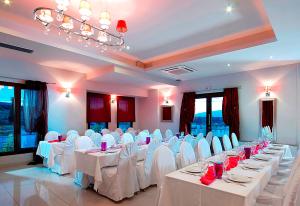 a banquet hall with white tables and white chairs at Orfeas Land in Kormísta
