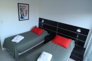 2 Einzelbetten in einem Zimmer mit roten Kissen in der Unterkunft Josefina in Ushuaia
