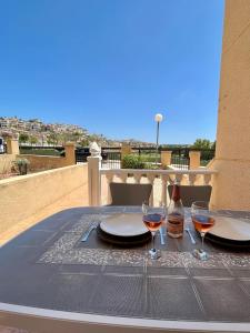 un tavolo con due bicchieri e una bottiglia di vino di Tranquil Self Catering Golf Course Apartment ad Alicante