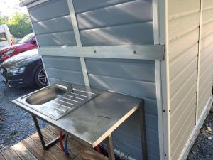 a sink in a shed next to a car at Clos Des Monts in Saint-Martin-des-Besaces