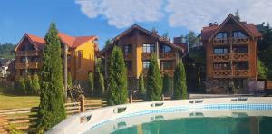 a large house with a swimming pool in front of it at Karpatski Zori Hotel in Bukovel