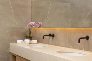 a bathroom with two sinks with flowers on the counter at Atlantica Bay - Adults Only in Limassol
