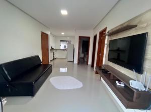 a living room with a black leather couch and a flat screen tv at TAPERAPUAN in Porto Seguro