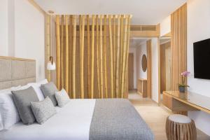 a bedroom with a white bed and a television at Atlantica Bay - Adults Only in Limassol