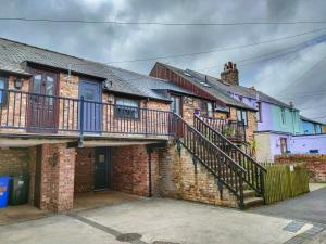a brick house with a balcony and a staircase at The Old Bakery Seahouses in Seahouses