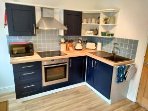 a small kitchen with blue cabinets and a sink at The Old Bakery Seahouses in Seahouses