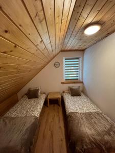 two beds in a room with a wooden ceiling at Leśne zacisze in Sucha Rzeczka