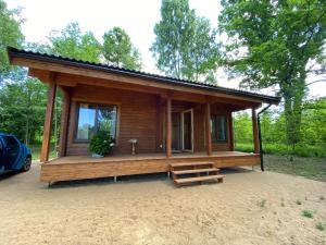 a small wooden cabin with a porch in the woods at Mikmari in Tūja