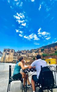two people sitting at a table in front of the coliseum at The Castle View Homestay in Būndi