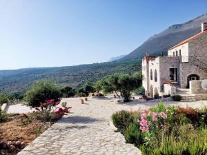 a stone walkway next to a building with flowers at Althea Village in Pyrgos Dirou