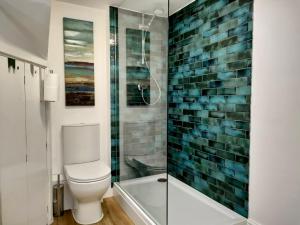 a bathroom with a toilet and a glass shower at The Old Bakery Seahouses in Seahouses