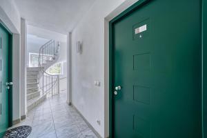 una puerta verde en un pasillo con una escalera en City Café - CENTRAL Apartment, en Brunico