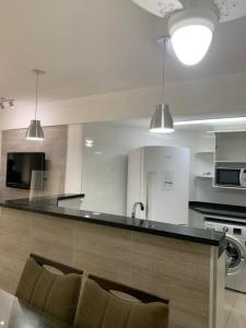 una cocina con encimera con sillas. en Apartamento Veleiros da Ilha - Praia do Tombo, en Guarujá
