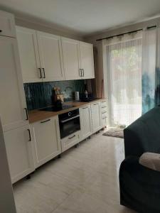 a kitchen with white cabinets and a large window at Domek przy Kasztanowej in Szczyrk