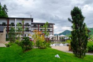 um hotel com um jardim em frente a um edifício em Piatra Pinului Ski & Spa em Gura Humorului