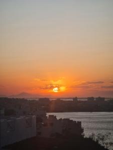 a sunset over the water with buildings and a city at Casa Mar da Grécia in Arraial do Cabo
