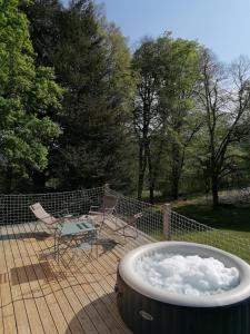 un bain à remous sur une terrasse avec des chaises et une clôture dans l'établissement Monchateau étoilé, hébergement insolite avec Spa, à Merlas
