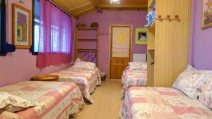 three beds in a room with purple walls at Casa Rural: La Casa Mágica de Gredos in Madrigal de la Vera
