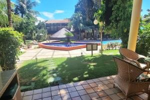 a backyard with a pool and chairs and a building at Solar de Pipa Elegance Flat - Frente Piscina in Pipa