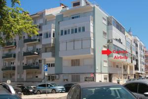 un edificio alto con coches estacionados frente a él en Apartamento Familiar em Zona Histórica de Lisboa, en Lisboa