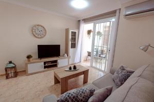 salon z kanapą i telewizorem w obiekcie Apto ACHE, acogedor apartamento de 66 m con terraza, aire acondicionado y parking privado gratuito w mieście Los Abrigos