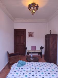 a bedroom with a bed and a bench and a chandelier at Imsouane Surf Paradise in Imsouane