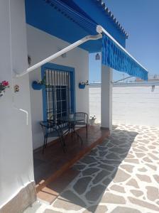 a patio with a table and a blue roof at MYKONOS entre cepas in Sanlúcar de Barrameda