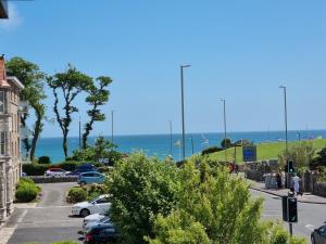 a street with cars parked in a parking lot next to the ocean at HighTide - 2 bed with parking, balcony & sea view. in Swanage