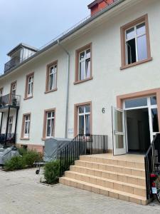 une grande maison blanche avec un escalier en face de celle-ci dans l'établissement Ferienwohnung Basner, à Lahr/Schwarzwald