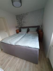 um quarto com uma cama grande e lençóis brancos em Ferienhaus Dani em Bad Frankenhausen